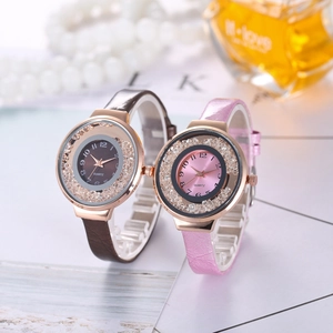 Close-up of rose gold quartz watches with crystal accents and leather straps on white table