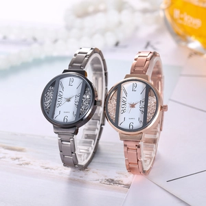 Close-up of quartz watches with diamond accents beside a pearl necklace and perfume