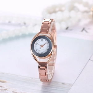 Elegant rose gold women's quartz watch with a dual-tone dial beside a pearl necklace
