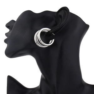 Detailed close-up of triple-layered silver hoop earrings with a polished metallic finish