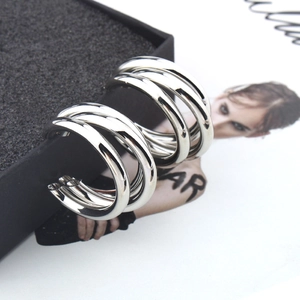 Detail of silver triple-layered semi-circle metal stud earrings with polished finish