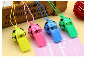 Close-up of four colorful plastic soccer whistles in yellow, pink, blue, and green