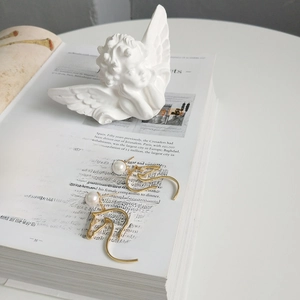 Detail of golden horse head earrings with white pearl and rhinestones on a book