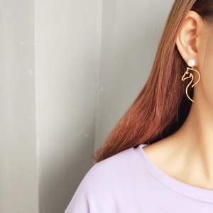 Detailed close-up of a golden horse head outline earring featuring a white shell pearl bead