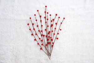 Detail of red artificial berry stems with glossy texture on white plush background