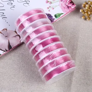 Stack of ten pink elastic beading cord rolls on white spools for DIY jewelry making