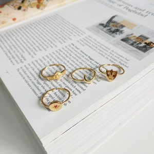 Close-up of four gold 925 silver rings on an open book including a BABY engraved band