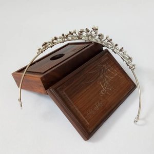 Detail of silver alloy crown with floral motifs and white pearls on wooden gift box