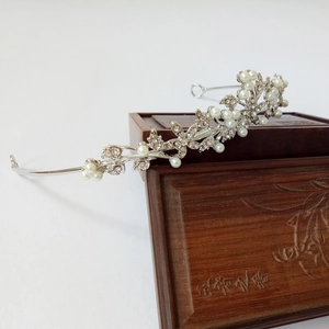 Detail of silver alloy tiara with white pearls and rhinestones on a vintage box