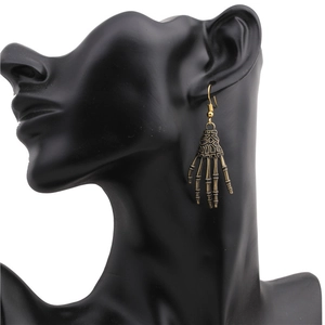 Detailed view of gothic skeleton hand earrings with bronze finish on a black model