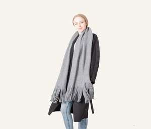 Close-up of thick grey tassel scarf on model showing soft faux cashmere texture