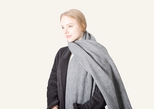 Close-up of grey long tassel scarf with thick wool-like texture on a black wool coat