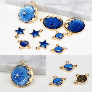 Detail view of blue enamel starry sky pendants with moon and planet charms for DIY jewelry