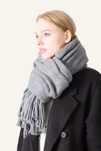 Detail of grey winter scarf with thick tassel fringe on wool-like knitted fabric