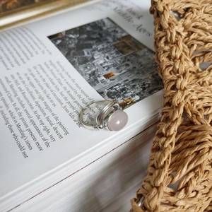 Close-up of vintage 925 silver ring with round pink quartz on open book pages