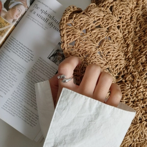 Macro detail of silver hugging hands ring on a vintage aesthetic lifestyle background