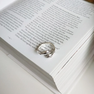 Close-up of S925 sterling silver hug ring on an open book, vintage aesthetic detail