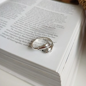 Detailed close-up of a sterling silver hugging hands ring on an open vintage book