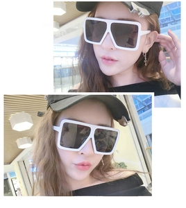 Close-up of oversized white square frame sunglasses with dark lenses on a model