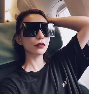 Close-up of black oversized square sunglasses worn in a lifestyle cabin setting
