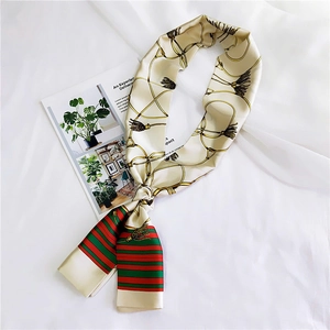 Detail shot of silk scarf with golden chain pattern and green red stripes on beige