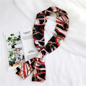 Detail of silk scarf tied in a knot featuring classic belt and chain patterns