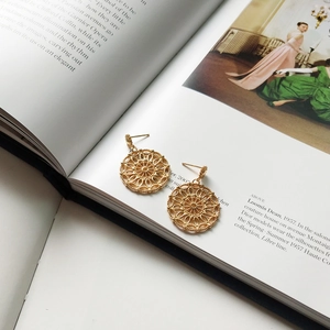 Detailed view of gold mandala hollow earrings on a high-fashion editorial background