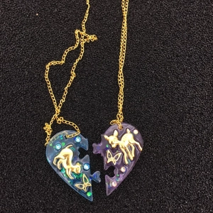 Détail de pendentifs cœur en résine époxy avec motifs chat bleu et cerf violet