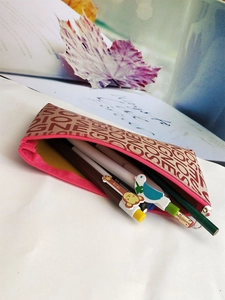 Detail of canvas pouch with pink zipper and repeat letter jacquard pattern