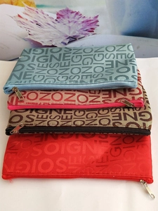 Stack of zipper cosmetic bags in four colors with repetitive NEZO letter patterns
