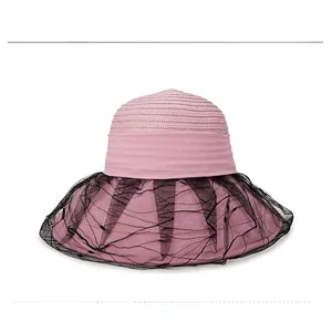 Detail of pink straw sun hat with black lace mesh trim and woven fiber texture