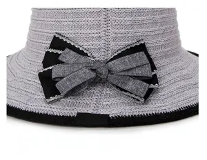 Close-up of the woven sun hat featuring a bicolor bow and brand label detail