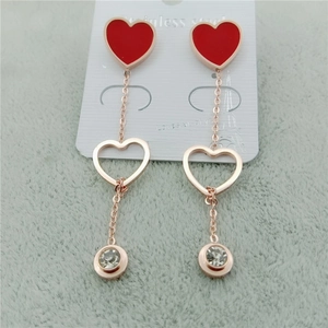 Détail de boucles d'oreilles cœur en acier or rose avec émail rouge et pendentif en zircon