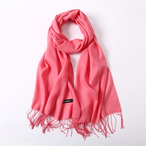 Detailed view of pink cashmere-like scarf showing soft fabric texture and fine fringe trim