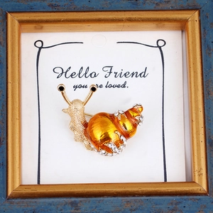 Detailed close-up of snail brooch with amber shell and sparkling crystal accents