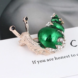 Macro view of gold snail brooch with green enamel shell and sparkling white rhinestones