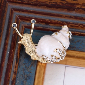 Macro shot of snail brooch with gold alloy base and sparkling rhinestones on wood