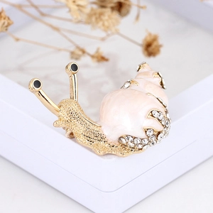 Detailed close-up of a golden snail brooch with pink enamel and sparkling rhinestones