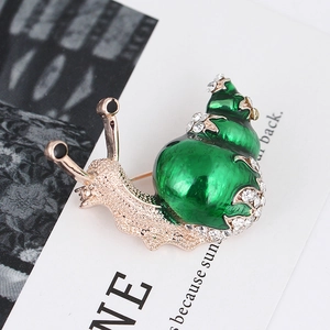 Macro view of green enamel snail brooch with gold plating and white sparkling crystals
