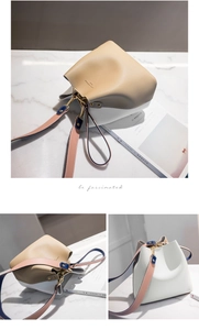 Detail of minimalist bucket bag showing two-tone leather texture and golden metal hardware