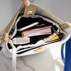 Contrast bucket bag with canvas drawstring insert and wide strap showing interior storage