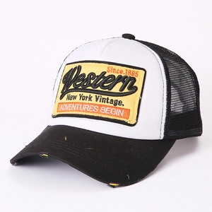 Detail der gelben Stickerei auf einer schwarz-weißen Mesh-Trucker-Cap mit Used-Effekt