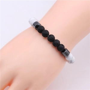 Detail of beaded stretch bracelet with black lava rocks and white turquoise on wrist