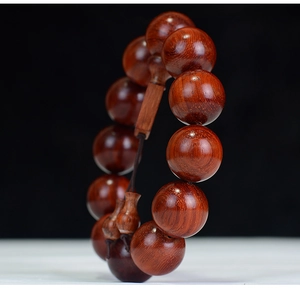 Macro shot of polished red rosewood prayer beads showing natural wood grain and texture