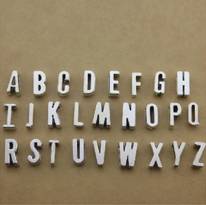 26 silver metal alphabet beads A-Z for DIY jewelry making displayed on brown paper