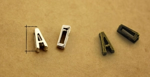 Macro detail of antique silver and bronze alloy letter pendants for DIY jewelry making