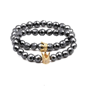 Detail of double set magnetic hematite bracelets with crown charms in gun black and gold
