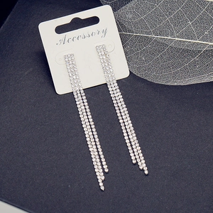 Close-up of elegant long silver tassel earrings with four rows of sparkling rhinestones