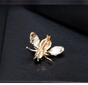 Macro shot of a golden bee brooch with sparkling crystals on a dark textured background