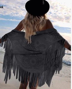 Detail of black fringe shawl featuring a bohemian tassel design against a beach sunset